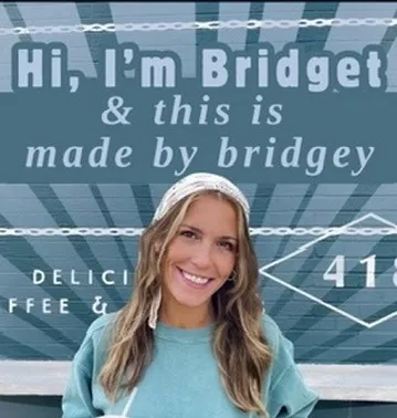 Bridget, the artist behind Made by Bridgey, smiling in front of a painted mural.